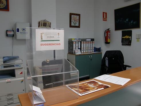 Recepción de las instalaciones de Formación y Empleo, con dos puestos de trabajo y un buzón de sugerencias en el mostrador.